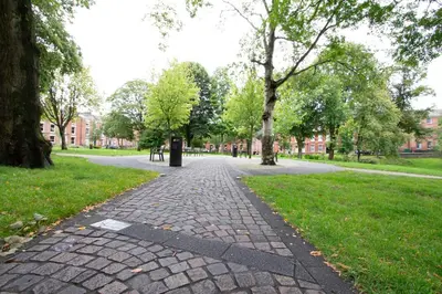 a brick path in a park with trees and buildings at Cosy Studio Apt in Preston near City Centre in Preston