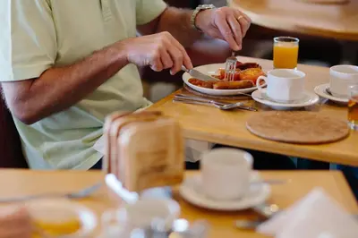 a man eating a plate of food on a table at Viking Hotel - Adults Only in Blackpool