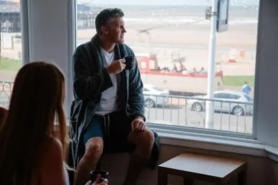 a man sitting in a window holding a cell phone at Viking Hotel - Adults Only in Blackpool