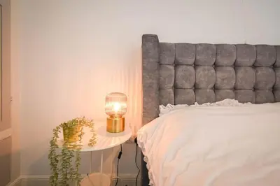 a bed with a lamp on a table with a plant at Home in the Heart of Accrington in Church