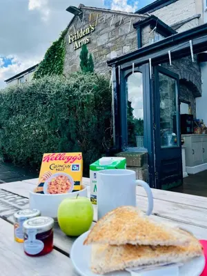 a table with a sandwich and a cup of coffee at Feildens Arms Hotel in Blackburn