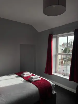 a bedroom with a bed with red curtains and a window at Feildens Arms Hotel in Blackburn