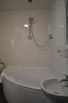 a bathroom with a bath tub and a sink at The New Guilderoy Hotel in Blackpool