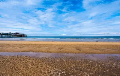 a beach with the ocean and a pier in the background at Norbreck Castle Hotel in Blackpool