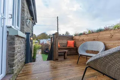 a wooden deck with a bench and chairs on it at 2 The Cottage in Upholland