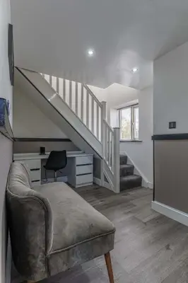 a living room with a couch and a staircase at 2 The Cottage in Upholland