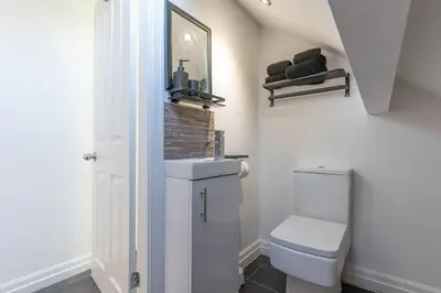 a white bathroom with a toilet and a mirror at 2 The Cottage in Upholland