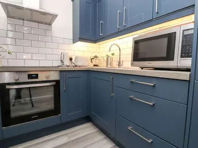 a kitchen with blue cabinets and a microwave at The Hideaway - Perfect couples retreat with Free parking on driveway in Lytham St Annes