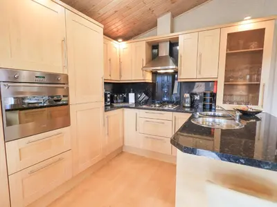 a kitchen with wooden cabinets and black counter tops at Our Happy Place in Carnforth