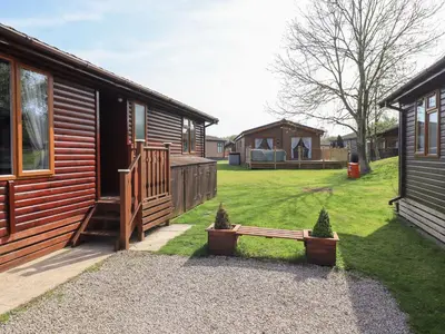 a log cabin with a bench next to a yard at Our Happy Place in Carnforth