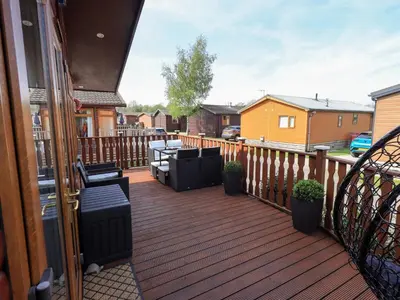 a deck with chairs and tables on a balcony at Our Happy Place in Carnforth