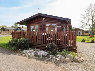 a small log cabin with a wooden fence at Our Happy Place in Carnforth