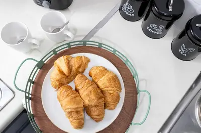 a plate of croissants on a counter with coffee cups at E&E's House in Cherry Tree
