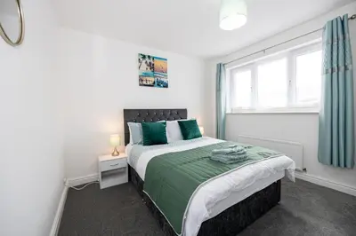 a bedroom with a bed with green sheets and a window at E&E's House in Cherry Tree