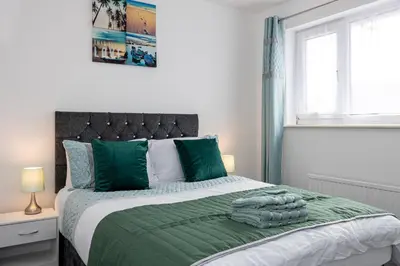 a bedroom with a bed with green sheets and pillows at E&E's House in Cherry Tree