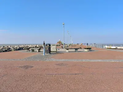 a pier with benches and the ocean in the background at Blue Sands in Morecambe