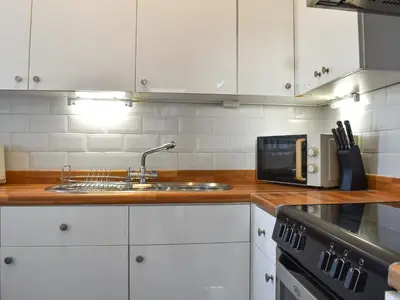 a kitchen with white cabinets and a sink and a microwave at Blue Sands in Morecambe