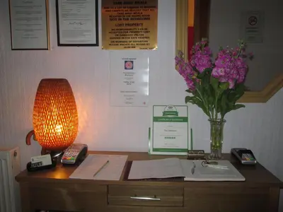 a desk with a lamp and a vase of flowers on it at The Middleton in Blackpool