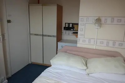 a bedroom with a white bed with a pink headboard at OLIVERS Strickley over 35 years only in Blackpool