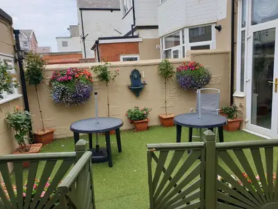 a patio with two tables and potted plants at OLIVERS Strickley over 35 years only in Blackpool