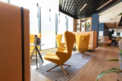 a lobby with yellow chairs and a table at Holiday Inn Blackpool by IHG in Blackpool