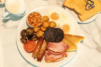 a plate of breakfast food with eggs sausage beans and toast at Holiday Inn Blackpool by IHG in Blackpool