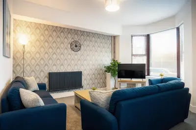 a living room with two blue couches and a tv at Spacious & Stylish 5 Bed with Free Street Parking in Morecambe