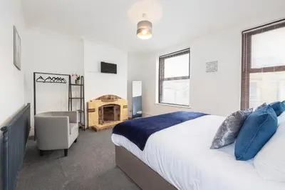 a bedroom with a bed and a chair and a fireplace at Spacious & Stylish 5 Bed with Free Street Parking in Morecambe