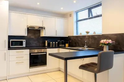 a kitchen with white cabinets and a black counter top at Spacious & Stylish 5 Bed with Free Street Parking in Morecambe