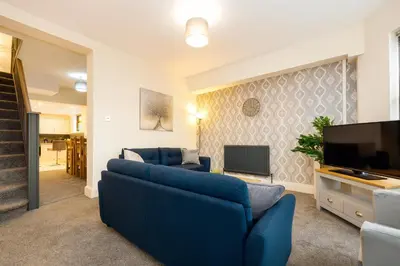 a living room with a blue couch and a tv at Spacious & Stylish 5 Bed with Free Street Parking in Morecambe