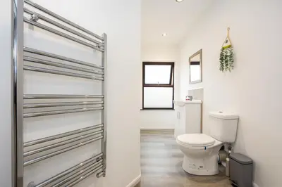 a white bathroom with a toilet and a door at Spacious & Stylish 5 Bed with Free Street Parking in Morecambe