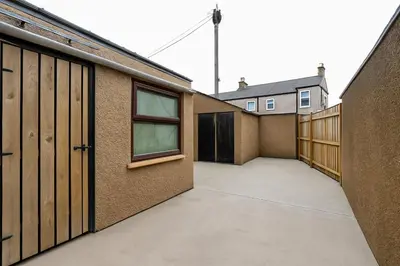 a row of garages with wooden doors on a building at Spacious & Stylish 5 Bed with Free Street Parking in Morecambe