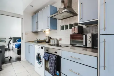 a kitchen with white cabinets and a washer and dryer at Kinetic Stays - Symphony Building in Liverpool