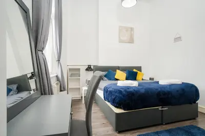 a bedroom with a bed with blue sheets and yellow pillows at Kinetic Stays - Symphony Building in Liverpool