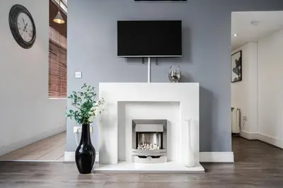 a living room with a fireplace with a tv above it at Kinetic Stays - Symphony Building in Liverpool
