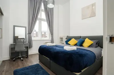 a bedroom with a bed with blue sheets and yellow pillows at Kinetic Stays - Symphony Building in Liverpool