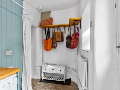 a kitchen with bags hanging on a wall next to a refrigerator at Quaint Cottage Retreat in Charming Ulverston - Pass the Keys in Ulverston