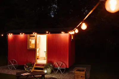 a red tiny house with lights on it at night at The Hamlet at Samlesbury Hall in Balderstone