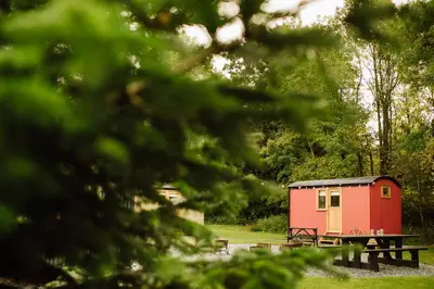 a red shed with a picnic table in the grass at The Hamlet at Samlesbury Hall in Balderstone