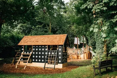 a small play structure with a roof and a playground at The Hamlet at Samlesbury Hall in Balderstone