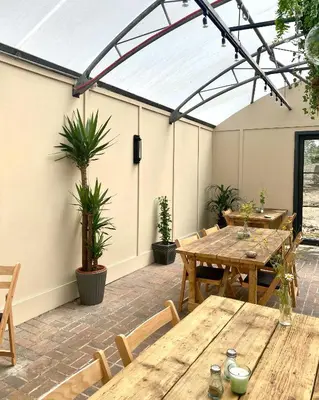 an outdoor patio with wooden tables and potted plants at The Gatehouse at Samlesbury Hall in Samlesbury