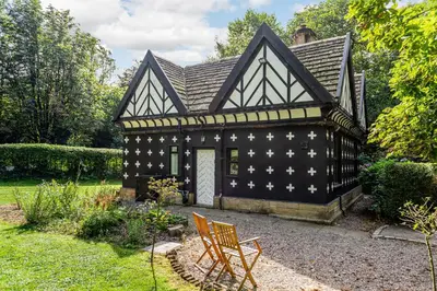 a black and white house with a chair in the yard at The Gatehouse at Samlesbury Hall in Samlesbury