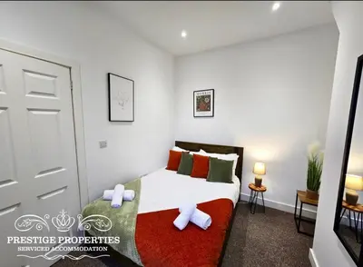 a bedroom with a bed with red and green pillows at 38 Gloucester street by Prestige Properties SA in Barrow in Furness