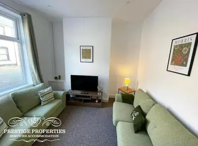 a living room with two green couches and a television at 38 Gloucester street by Prestige Properties SA in Barrow in Furness