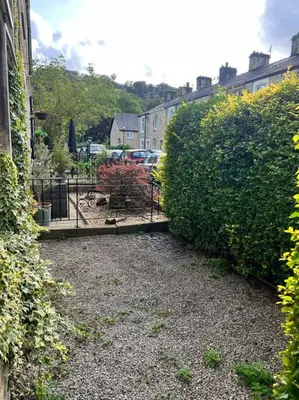 a garden with a fence and some bushes and buildings at Cottage in Whalley in Whalley