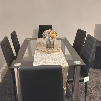 a table with chairs and a vase of flowers on it at 4 Double Bedroom House in Accrington sleeps 6 in Accrington