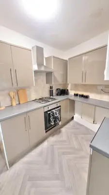 a kitchen with white cabinets and a black stove at 4 Double Bedroom House in Accrington sleeps 6 in Accrington