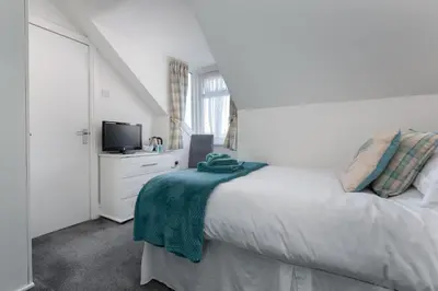 a white bedroom with a bed and a tv at The Beechcliffe Hotel - Over 35's Only in Blackpool