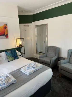 a hotel room with a bed and two chairs at The Beechcliffe Hotel - Over 35's Only in Blackpool