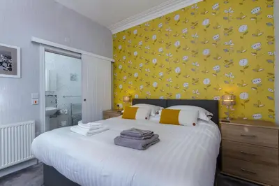 a bedroom with a white bed with a yellow wall at The Beechcliffe Hotel - Over 35's Only in Blackpool
